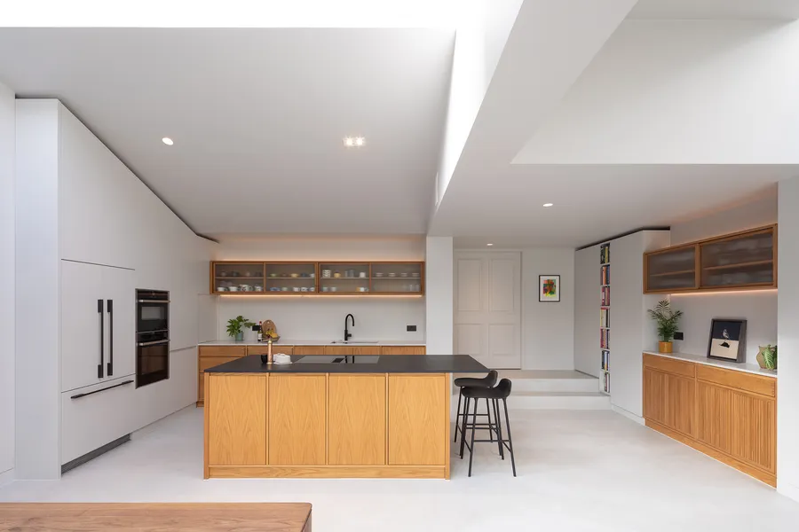 Open plan kitchen with oak island, white tall units and oak wall cabinets with reeded glass fronts.
