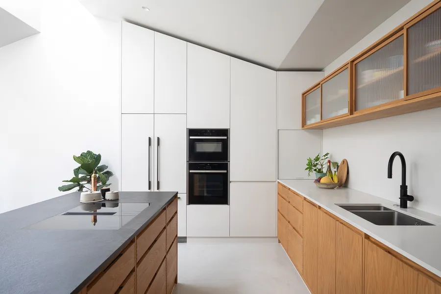 Galley view of the black granite island, built-in ovens and oak sink run under the sloping ceiling.