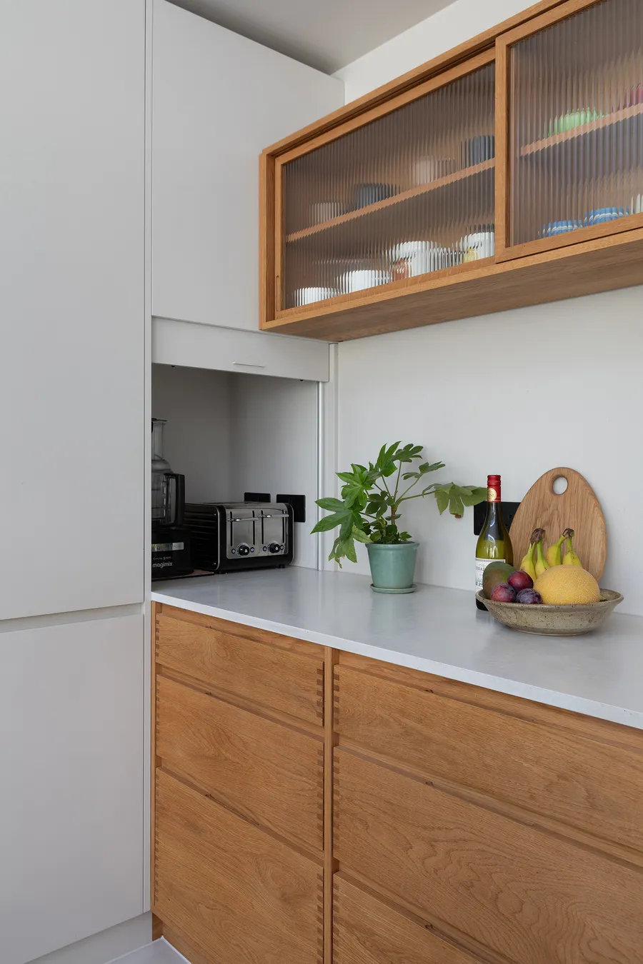 Appliance cupboard open to show a toaster on the white Caesarstone worktop above oak drawers.