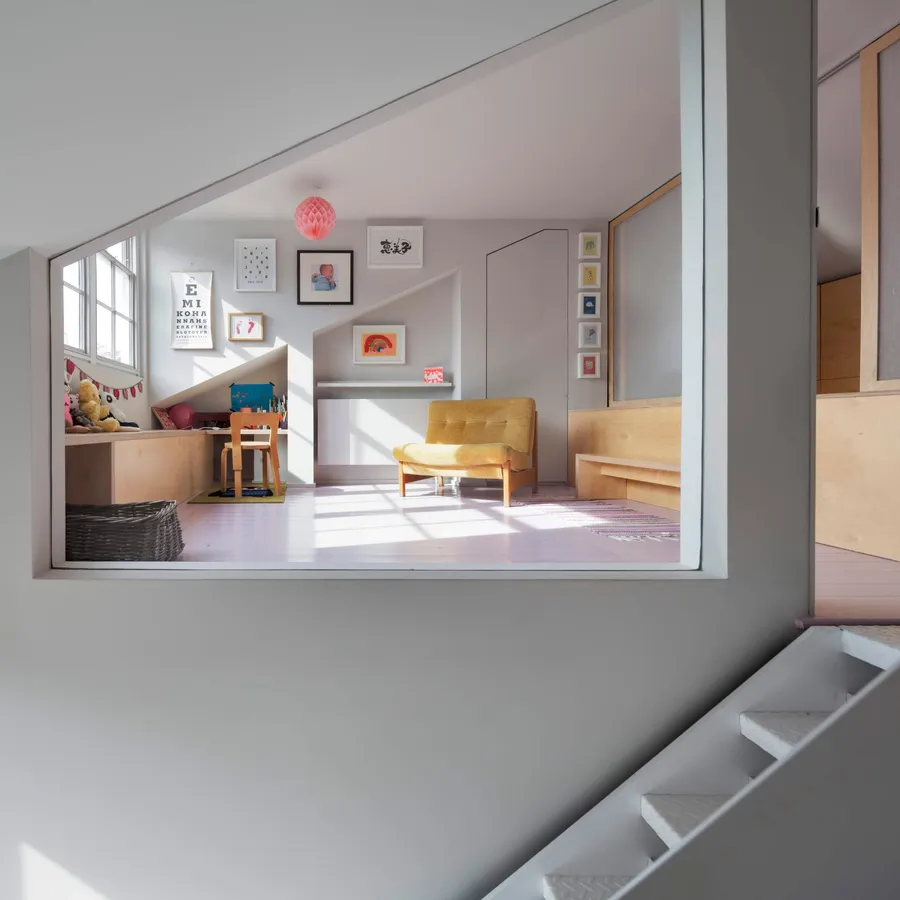 Child's playroom with birch plywood bench seating and desk, seen through a wall opening.