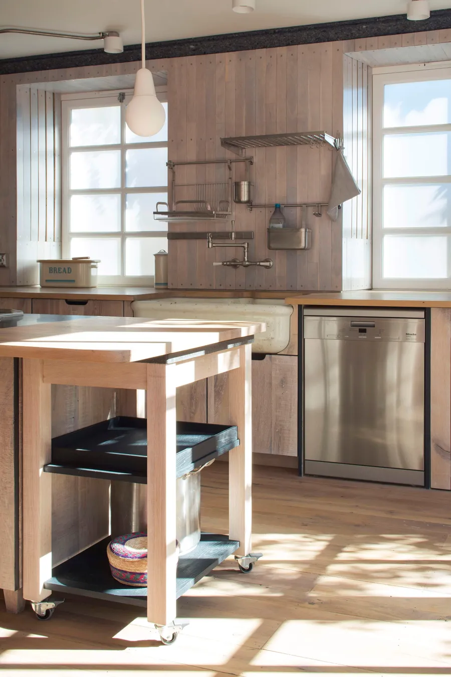 Side view of the oak trolley on castors pulled from the island, dishwasher and sink behind.