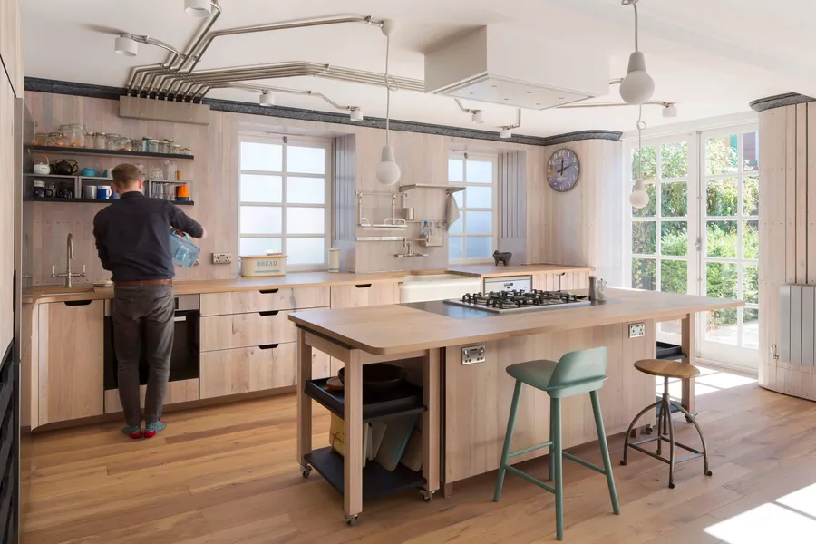 Person at the reclaimed oak worktop, island and stools in front, garden doors to the right.