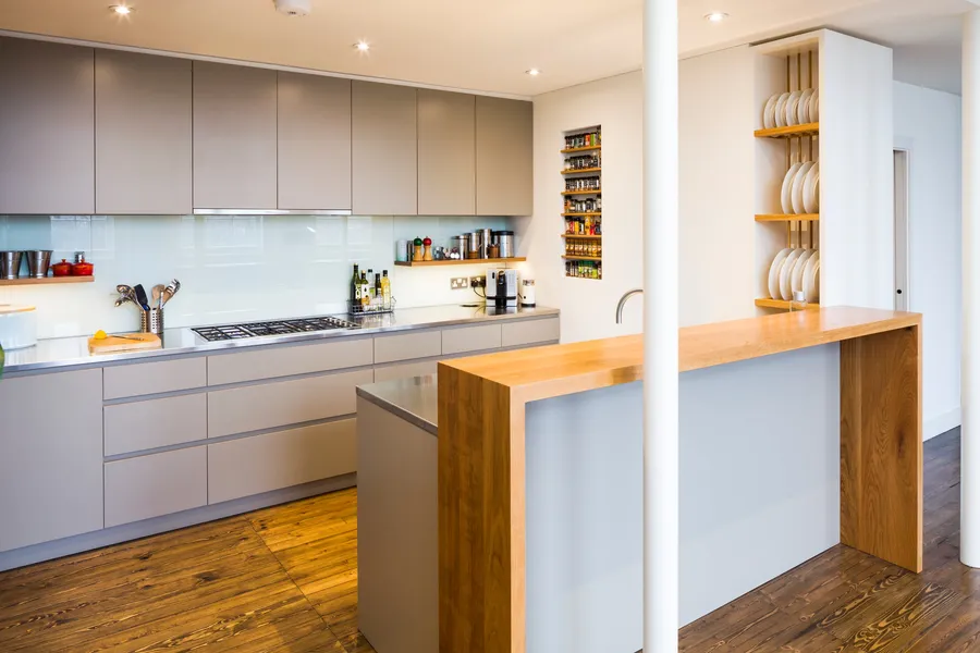 Modern kitchen with a mix of stainless steel and oak worktops, laminated plywood fronts and bespoke oak spice and plate racks.