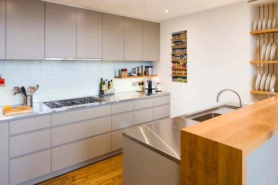 Modern kitchen with a mix of stainless steel and oak worktops, laminated plywood fronts and bespoke oak spice and plate racks.