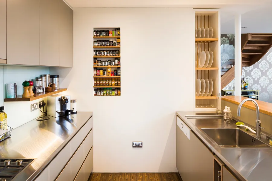 Modern kitchen with a mix of stainless steel and oak worktops, laminated plywood fronts and bespoke oak spice and plate racks.