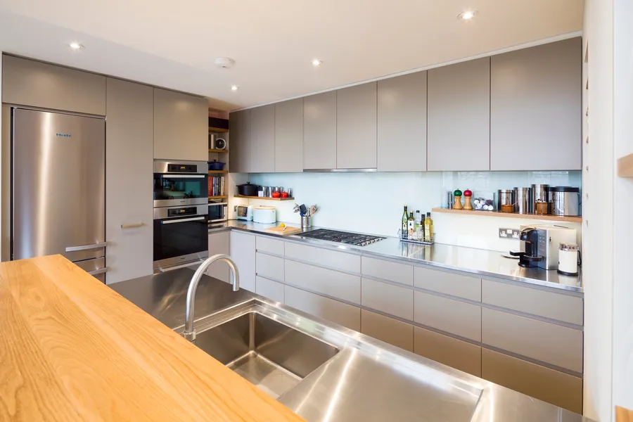 Modern kitchen with a mix of stainless steel and oak worktops, laminated plywood fronts and bespoke oak spice and plate racks.