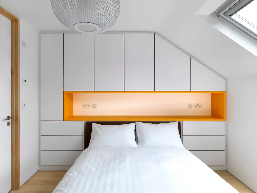 Modern bedroom wardrobe with white sprayed fronts and orange headboard.
