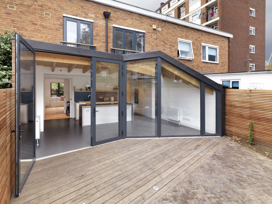 Glazed wall with kitchen and roof structure shot from the garden.