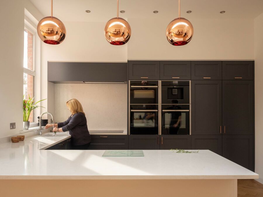 Modern kitchen with quartz worktops and shaker style fronts with copper handles and pendant lights..