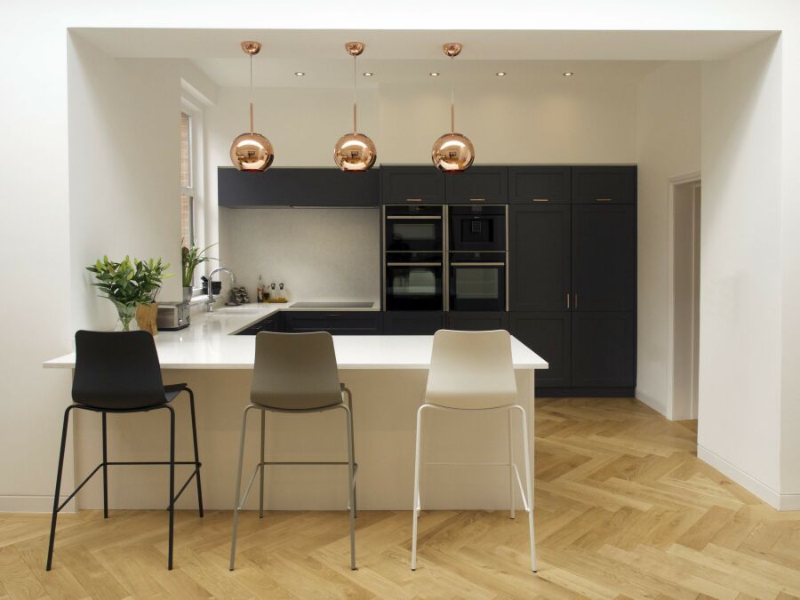 Modern kitchen with quartz worktops, breakfast bar and shaker style fronts with copper handles and pendant lights..