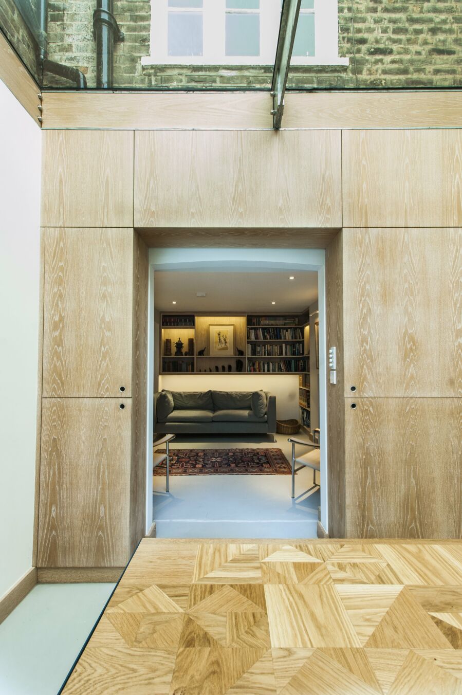 Limed oak veneered plywood dining room cabinetry, floating lounge library shelving with LED lighting..