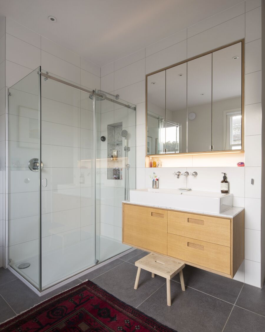 Bathroom with mirrored oak veneered plywood vanity unit and floating sink unit.