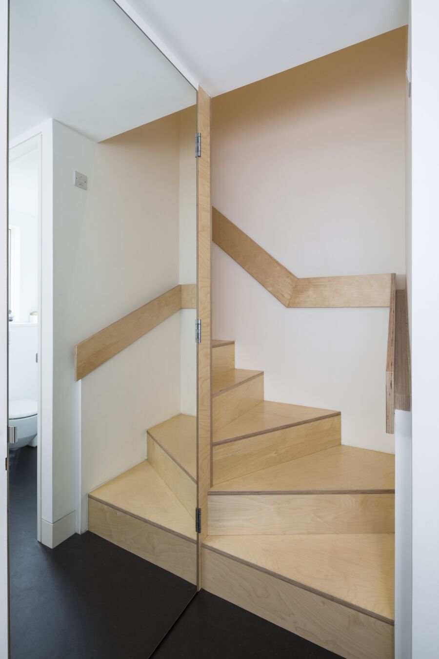 Birch plywood staircase with mirrored door reflection..