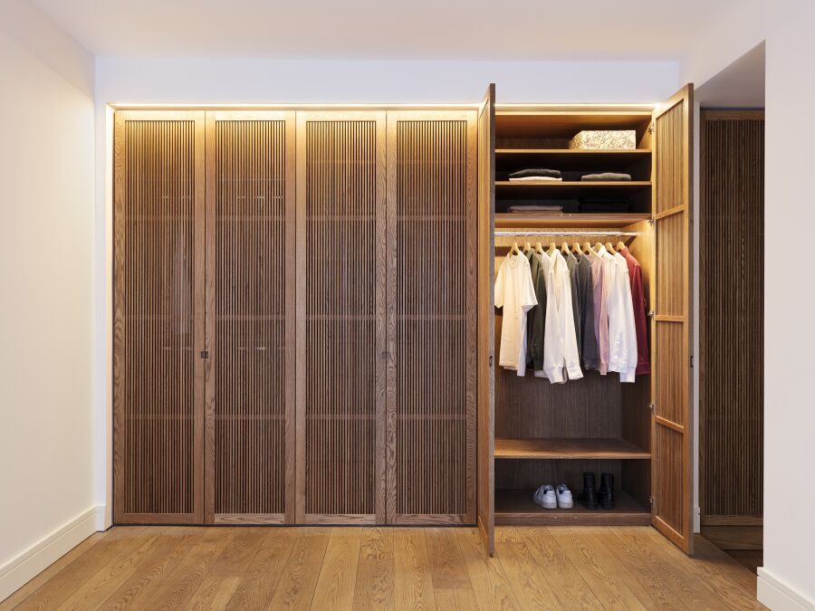 Master bedroom wardrobe with solid oak slatted doors , veneered oak interiors and LED lighting.