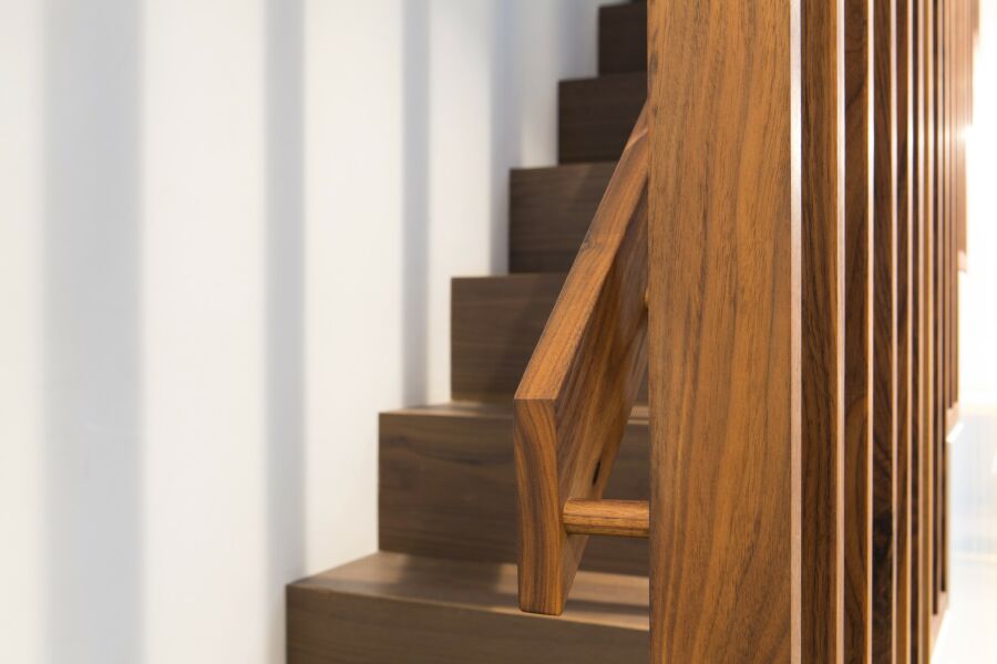​​A walnut staircase with solid walnut balustrade, hand rail and understairs storage detail..