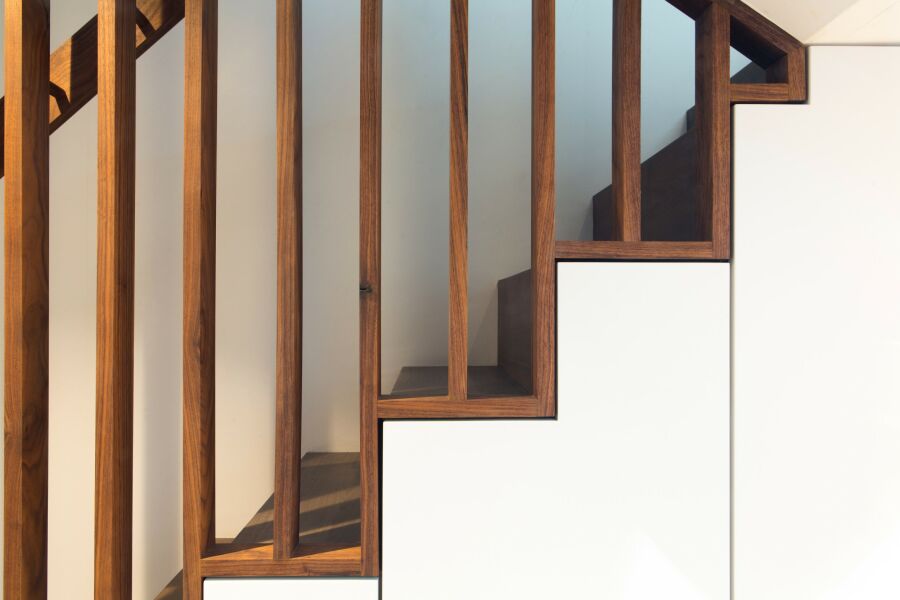 ​​A walnut staircase with solid walnut balustrade, hand rail and understairs storage detail..