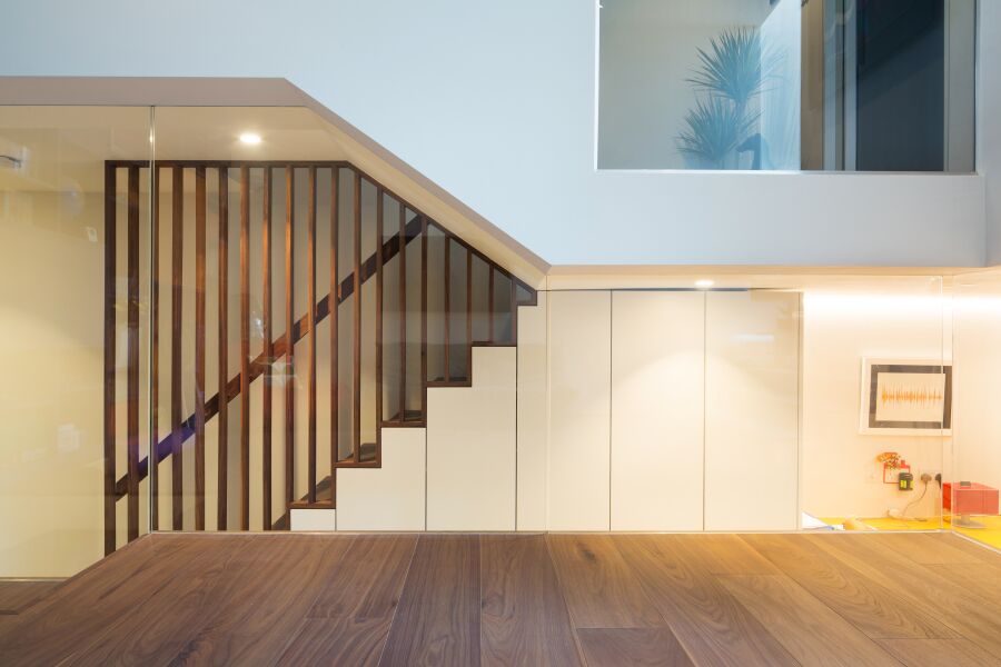 ​​A walnut staircase with solid walnut balustrade, hand rail and understairs storage detail..