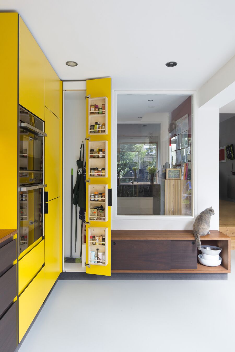 Kitchen with yellow laminate, stained Sapele on black Valchromat fronts and reclaimed solid Iroko worktops and bench seating..