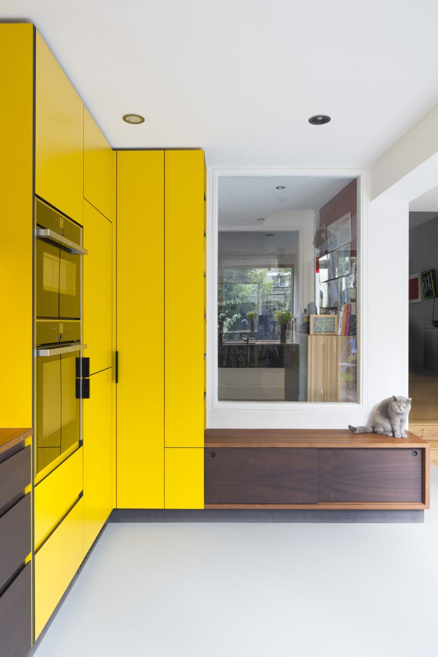 Kitchen with yellow laminate, stained Sapele on black Valchromat fronts and reclaimed solid Iroko worktops and bench seating..