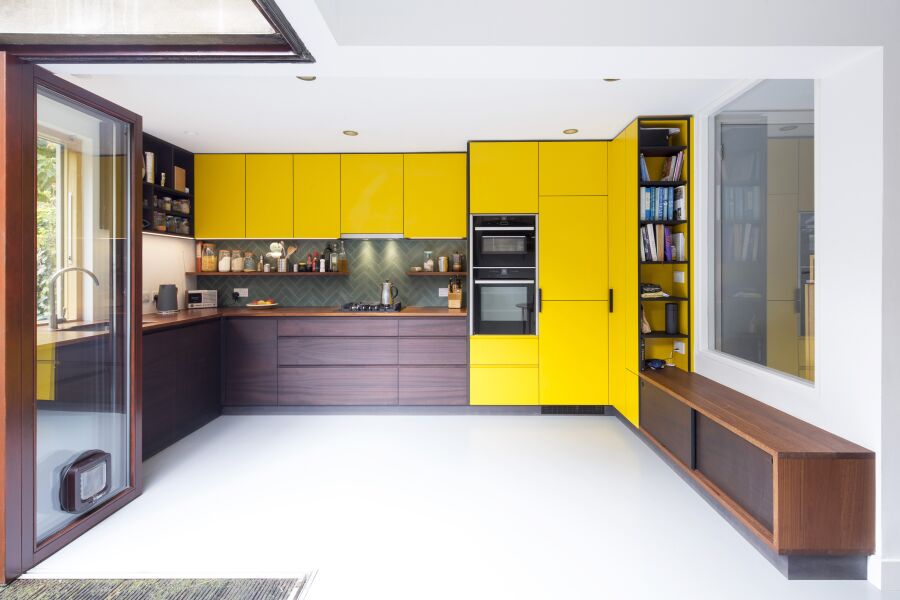 Kitchen with yellow laminate and stained sapele on black valchromat fronts. Reclaimed Iroko worktops and bench seating.