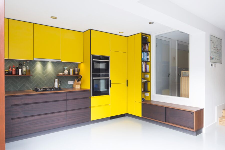 Kitchen with yellow laminate, stained Sapele on black Valchromat fronts and reclaimed solid Iroko worktops and bench seating..