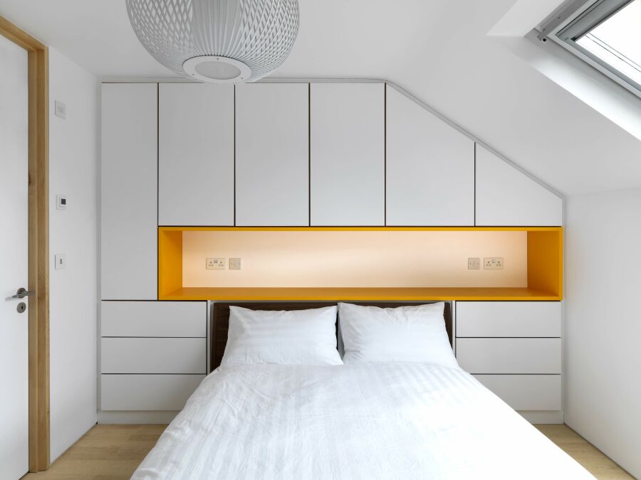 Modern bedroom wardrobe with white sprayed fronts and orange headboard..