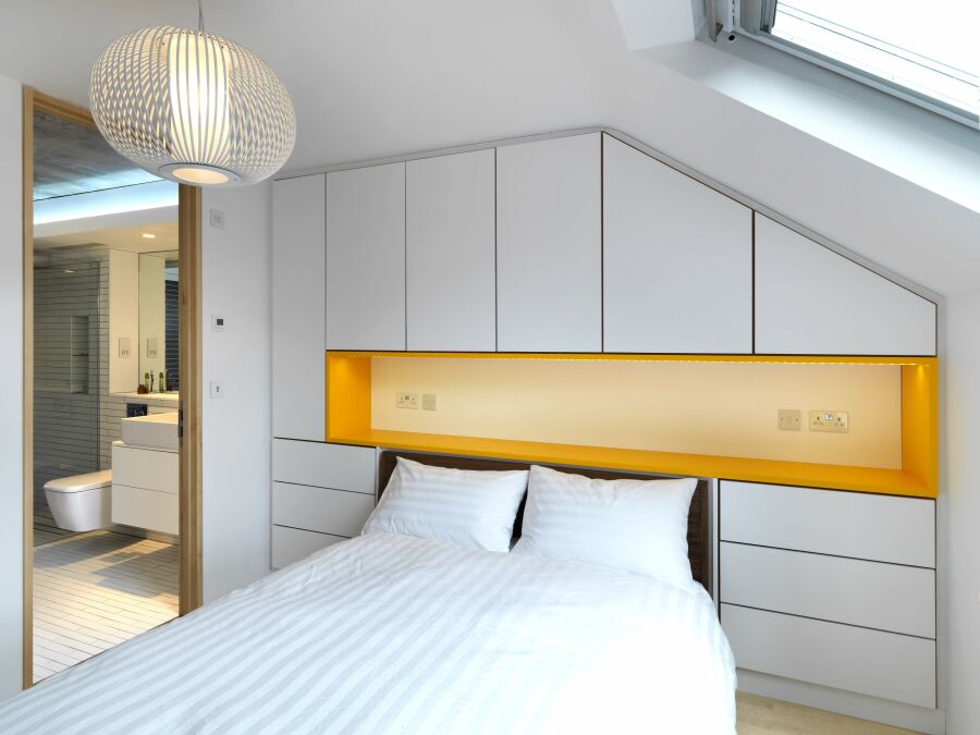 Modern bedroom wardrobe with white sprayed fronts and orange headboard..