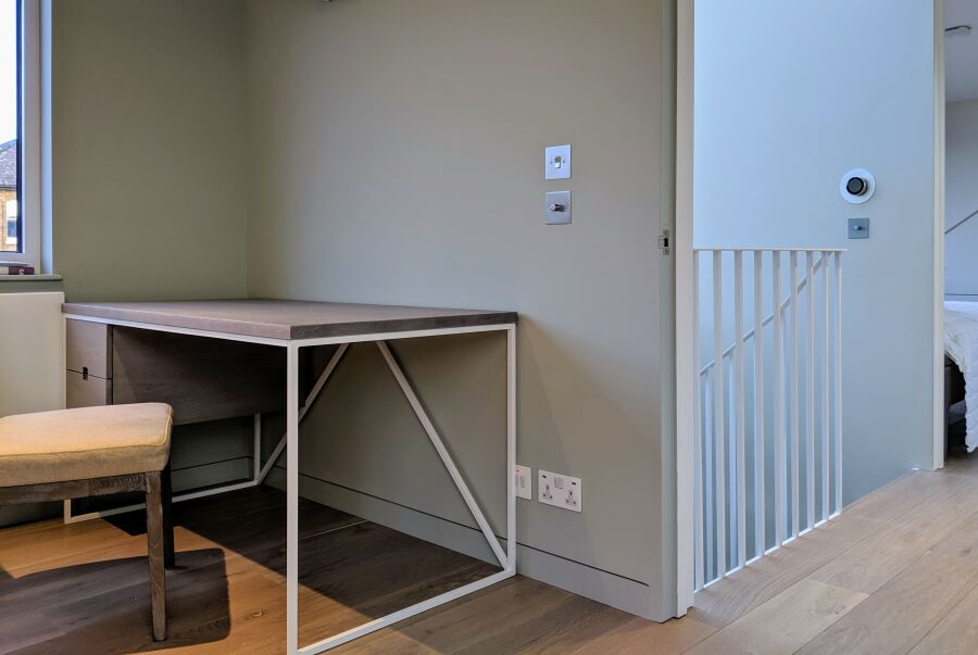 Powder-coated steel-framed desk with solid oak top and under-mounted floating drawer unit..